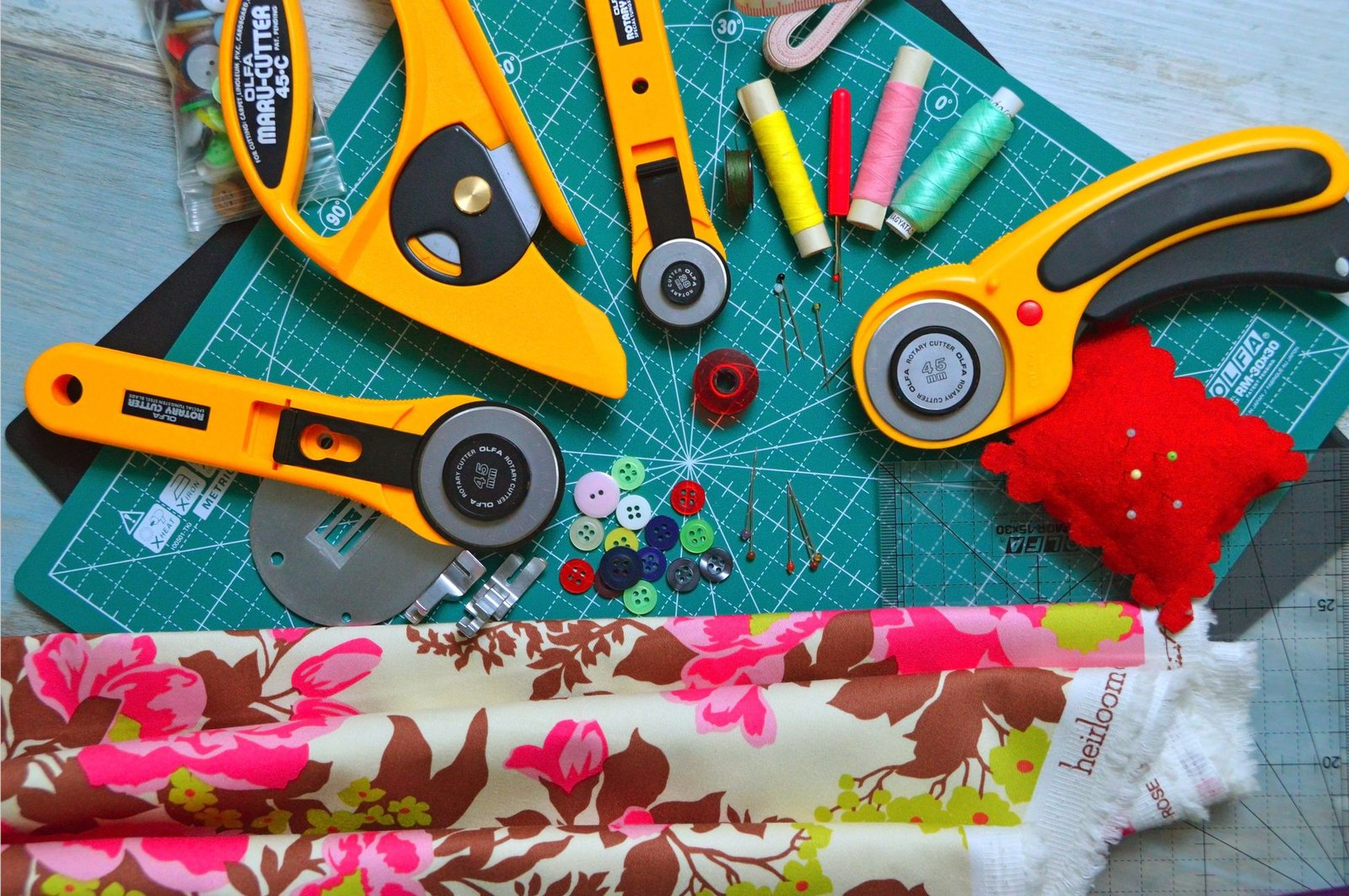 Sewing tools including a rotary cutter and scissors laid out on a fabric cutting mat