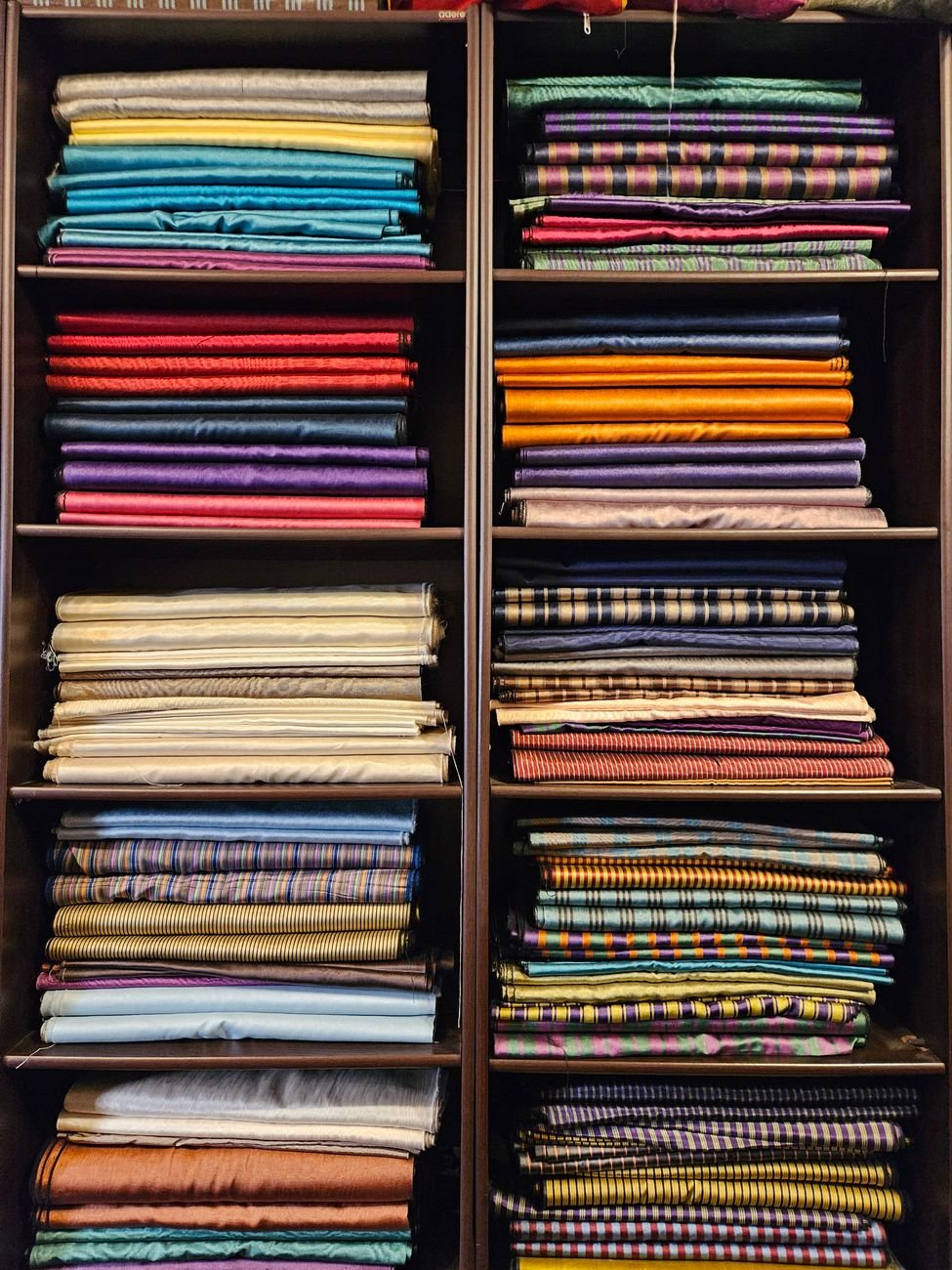 Folded bolts of stretchy knit fabric stacked on a fabric shop shelf