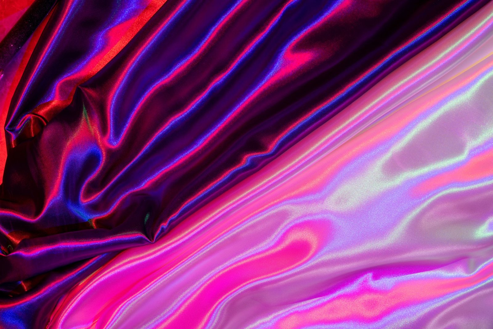 Iridescent satin fabric folds shifting between pink and blue tones