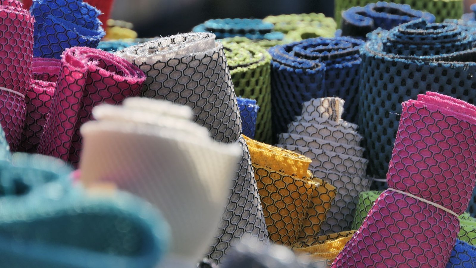 Rolls of colorful polyester mesh fabric stacked together