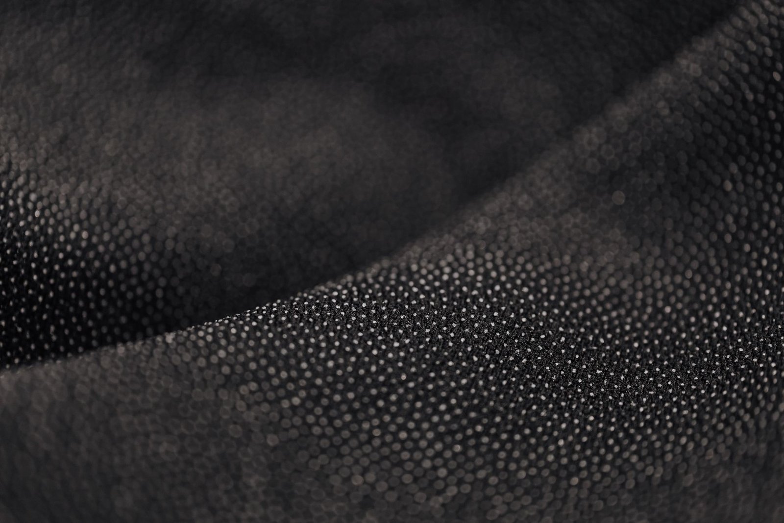 Close-up of a dark, dimpled scuba-knit texture typical of neoprene fabric facing