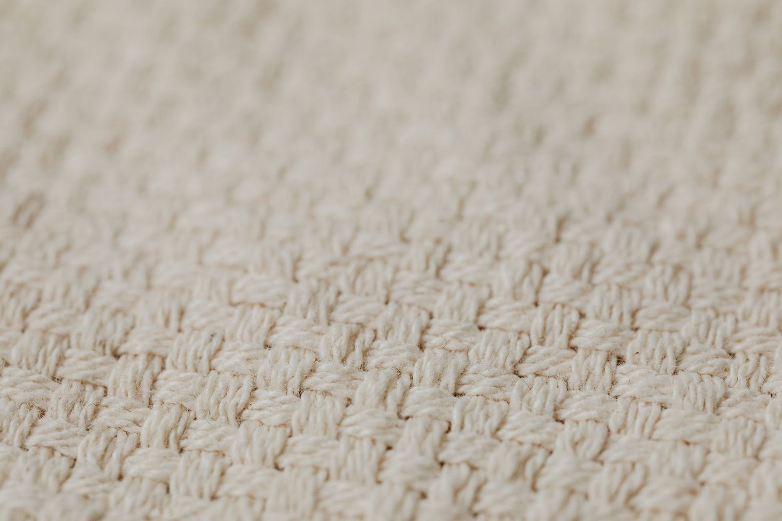 Macro close-up of a natural cream cotton fabric showing its tight basket weave structure