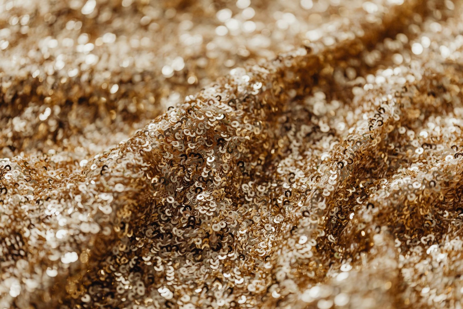 Close-up of sparkly gold sequin fabric showing individual sequins bunched in folds