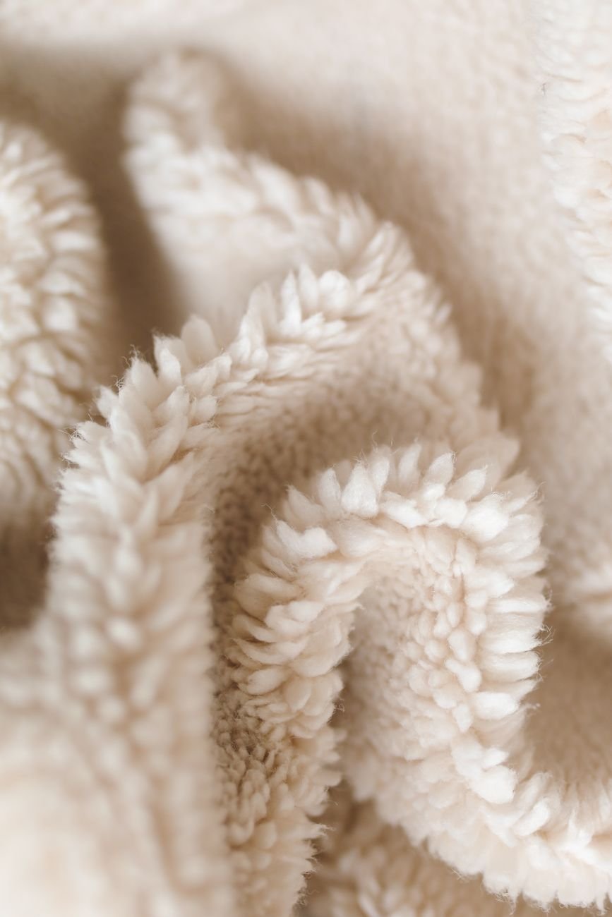 A folded sherpa fleece blanket showing its thick, looped pile texture