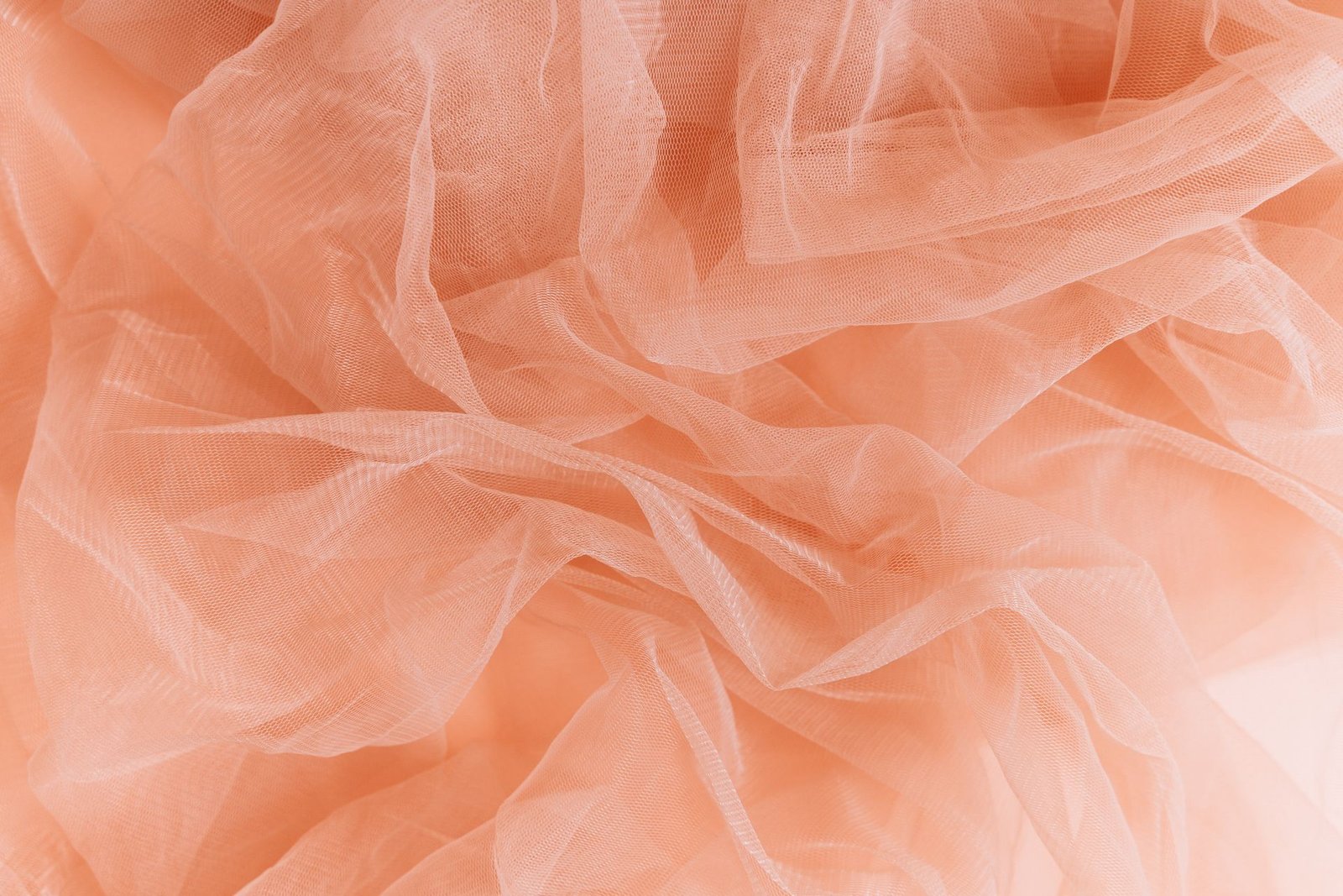 Soft folds of peach-colored tulle fabric layered together