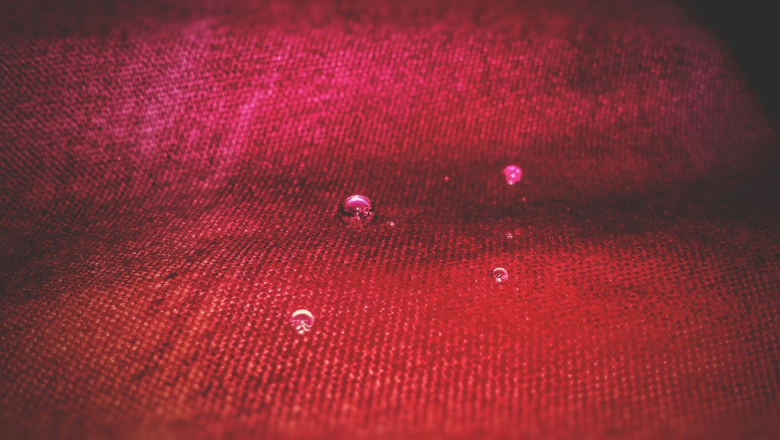 Water droplets beading on the surface of red water-repellent fabric