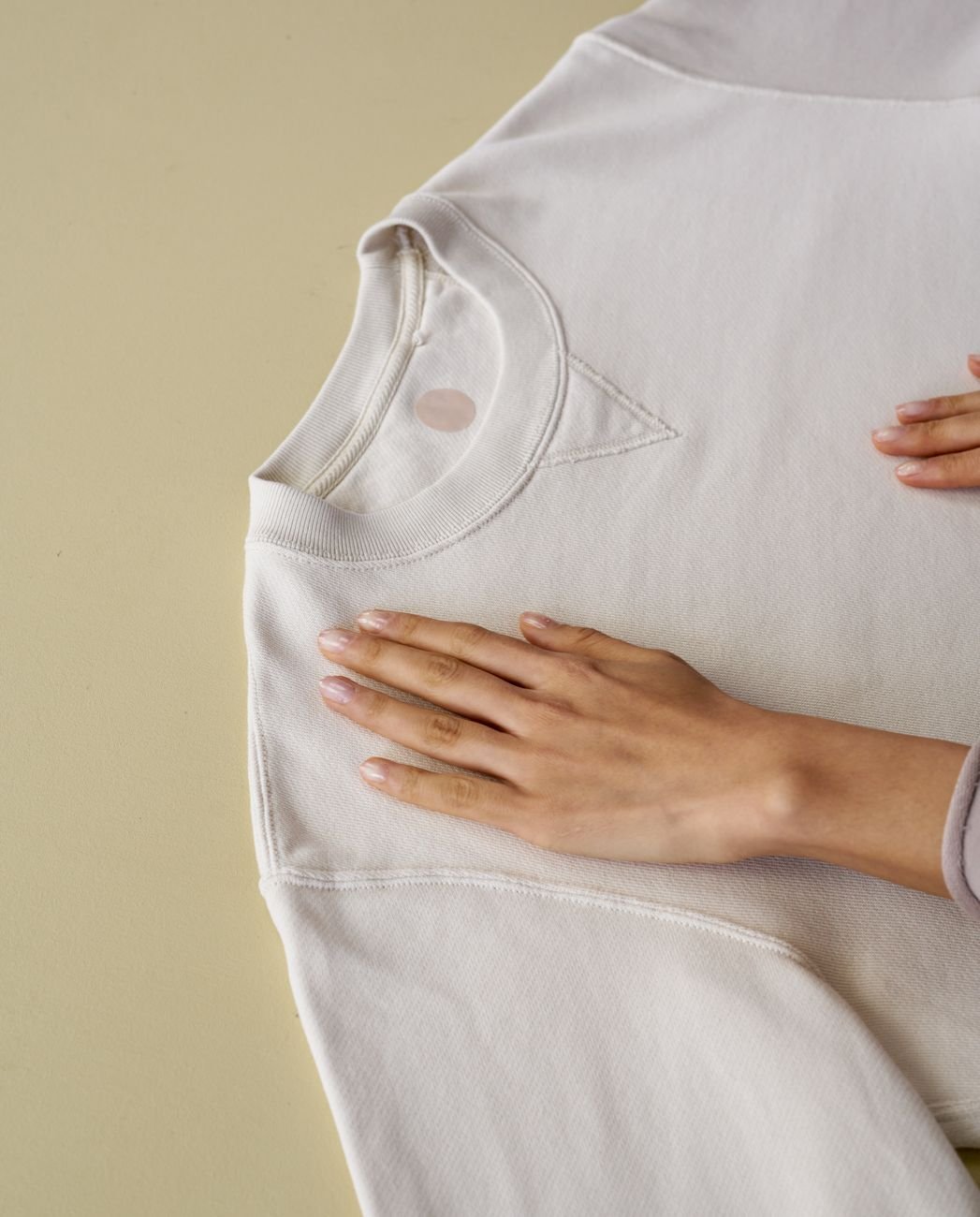 A hand gently placed on soft white cotton fabric, checking its texture