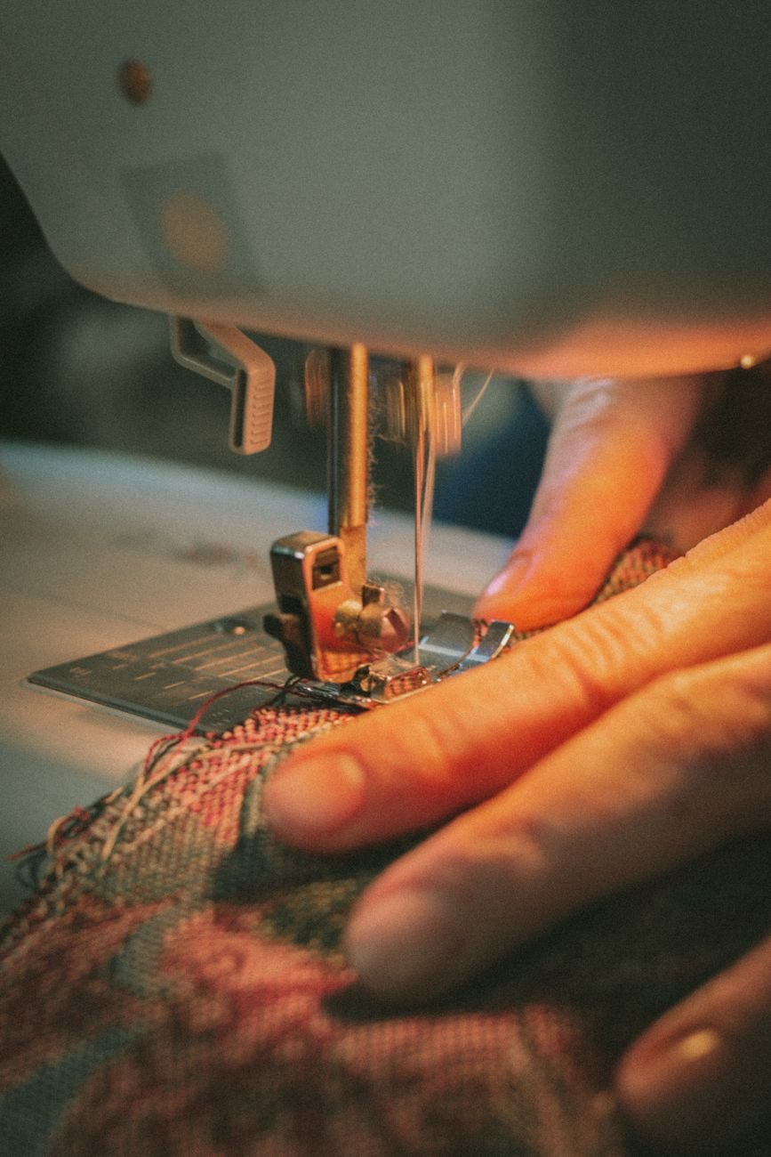 A hand guiding fabric under a sewing machine needle and presser foot