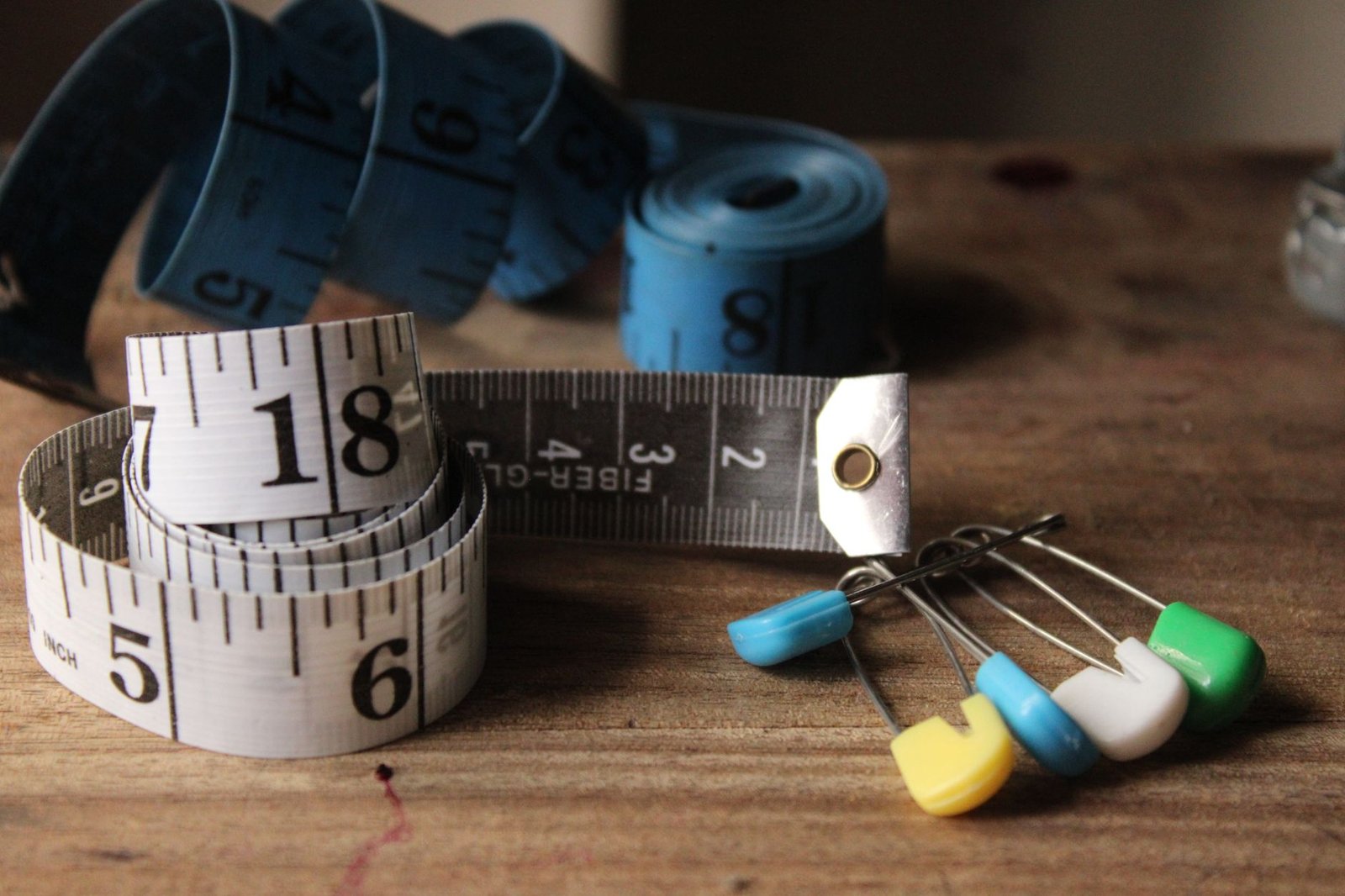 Tape measure and pins laid across a wooden surface