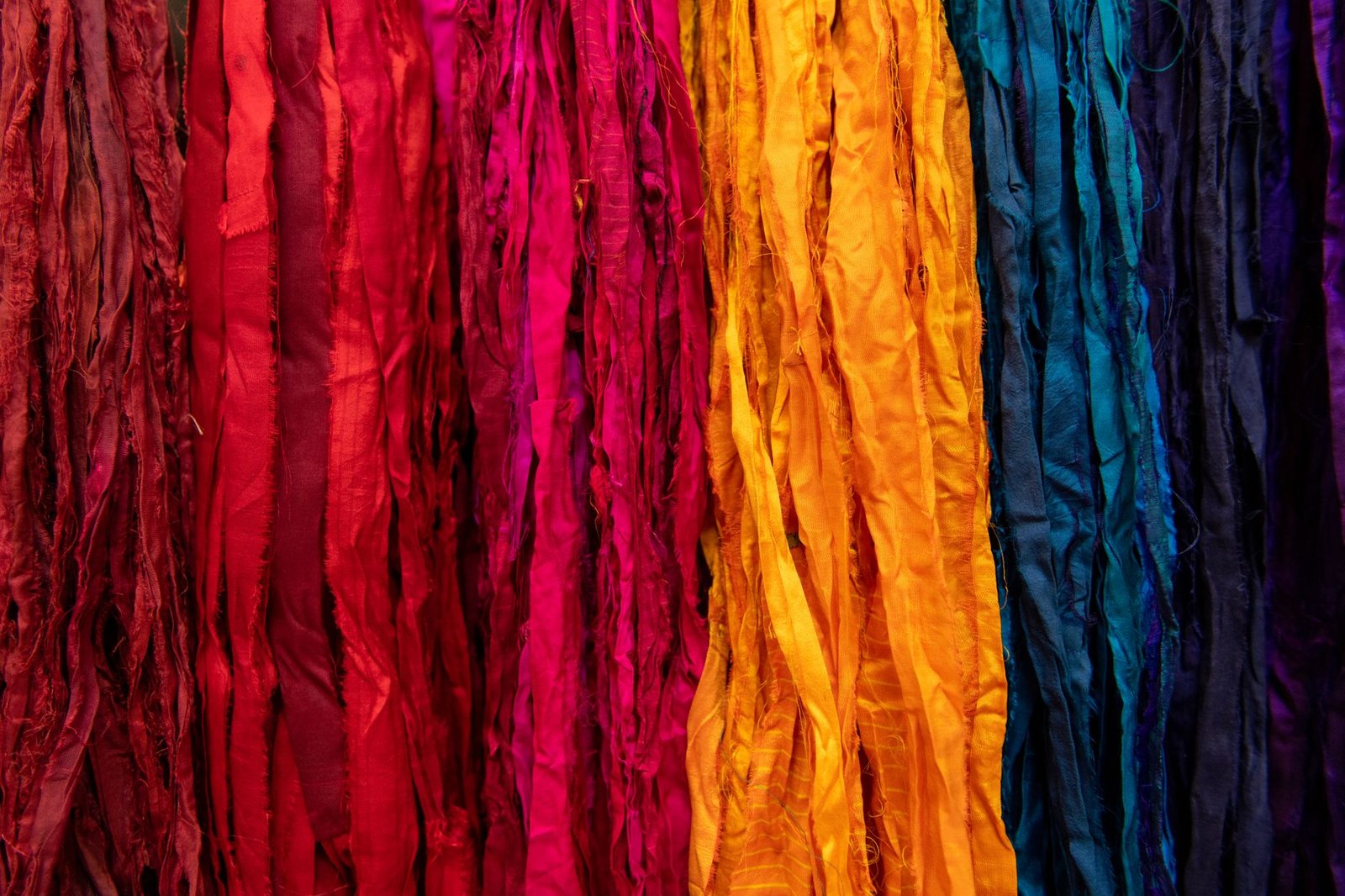 Hanging fabric strips arranged in a rainbow gradient from red to blue