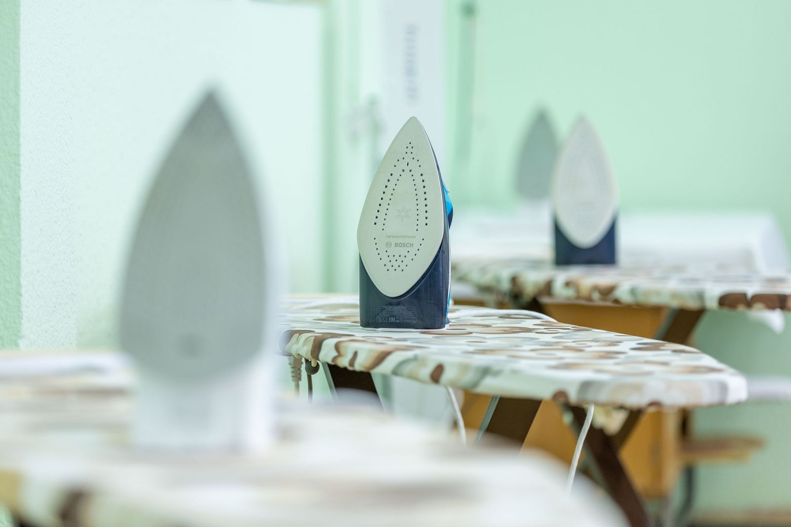 Rows of irons resting upright on ironing boards in a sewing classroom