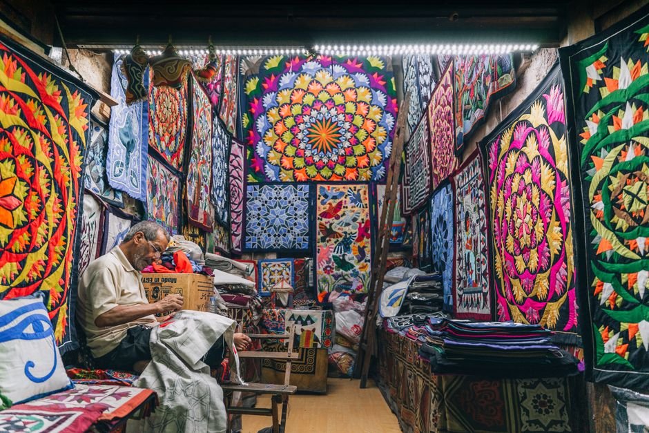 Craftsman hand-stitching colorful geometric quilted textiles in a workshop