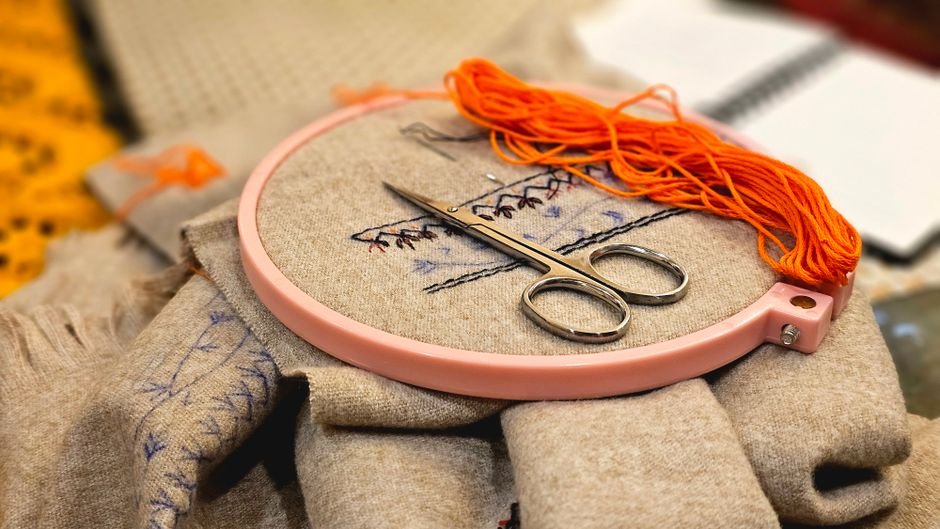 Cross stitch embroidery hoop with colorful thread showing a cross stitch kit for adults in progress