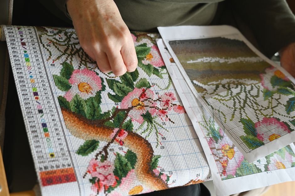 Framed cross stitch needlework close-up showing fine, detailed stitching