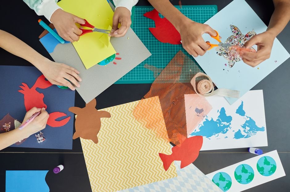 Kids using scissors and felt shapes at a craft table to make fabric stickers and decorations