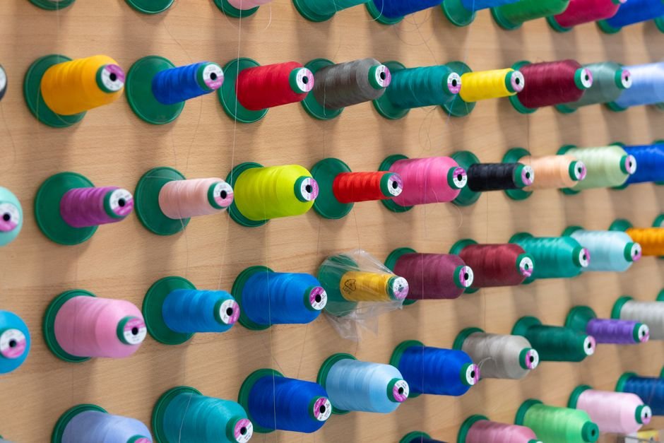 Rainbow of embroidery thread spools organized on a rack for color chart reference