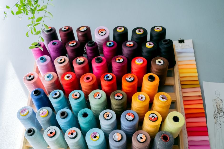 Machine embroidery thread cones organized on a shelf by color