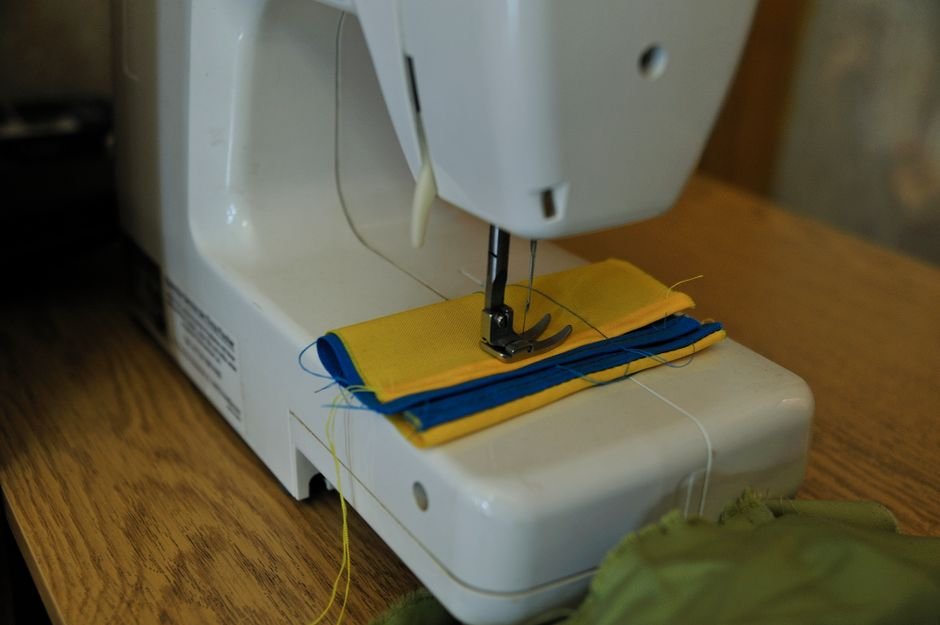 Sewing machine stitching folded yellow and blue fabric strips together for a jelly roll rug