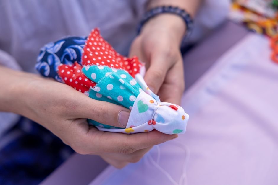 Hands piecing colorful polka-dot fabric squares together by hand for a beginner quilt