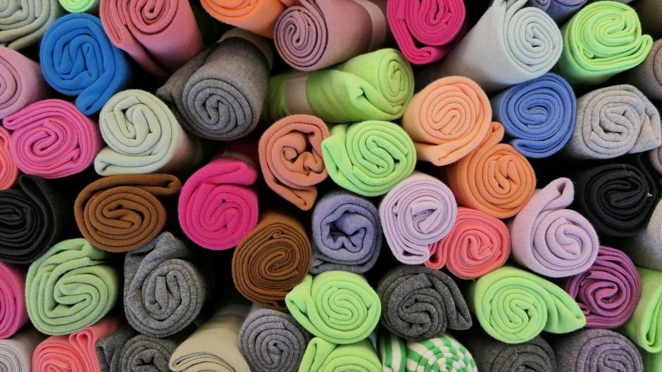 Rows of colorful rolled fabric bolts arranged together