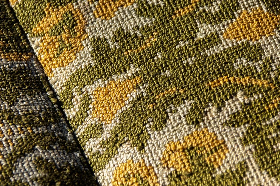 Olive and gold woven fabric texture showing a green-toned patterned weave