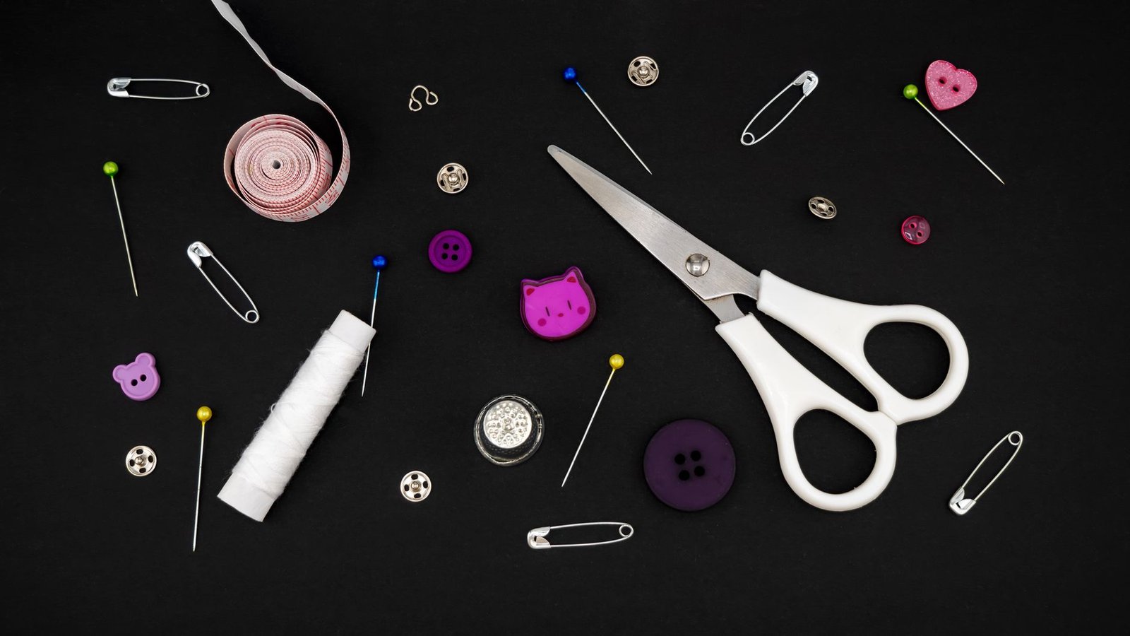 Sewing notions including a thimble, pins, and thread spools on fabric