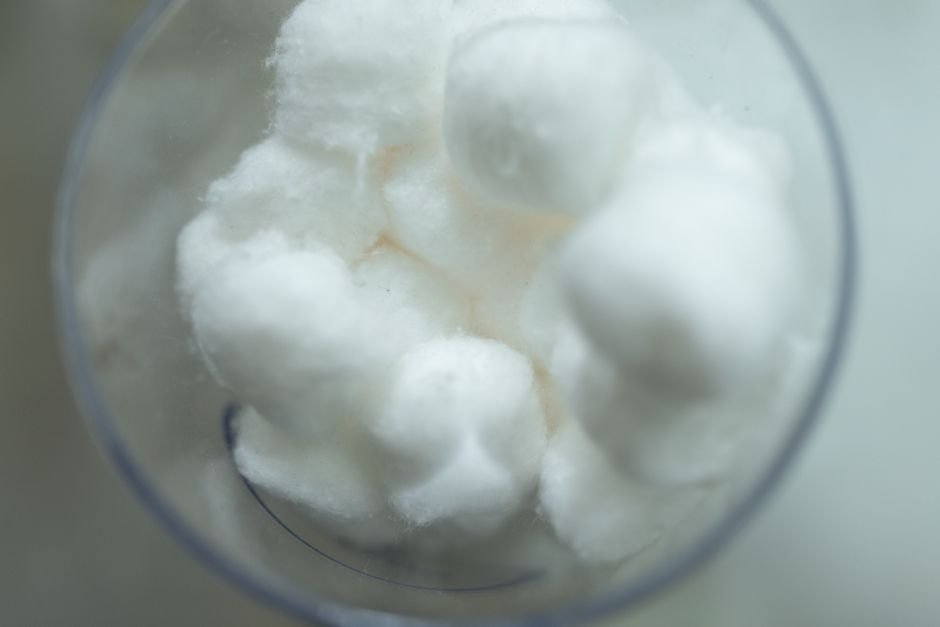 Soft white cotton balls in a glass showing a fluffy filling material similar to poly fill