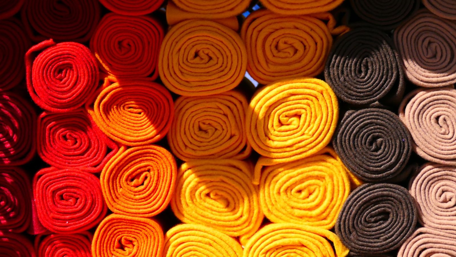 Rolled fabric in a warm gradient of red, orange, and yellow tones