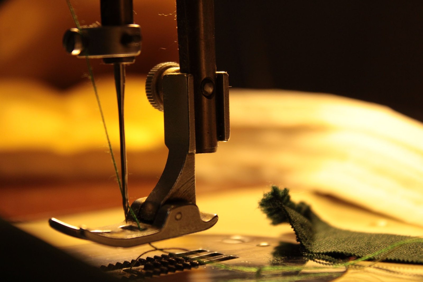 Sewing machine stitching a seam on green fabric