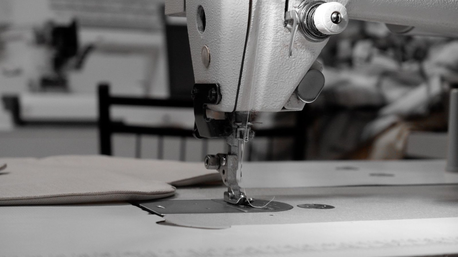 Industrial sewing machine stitching a beige bag panel