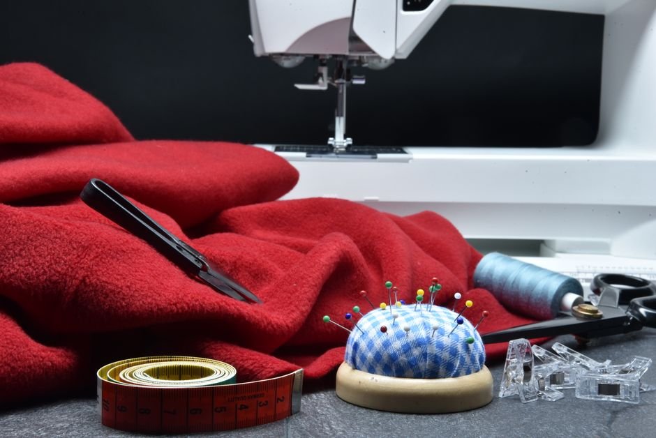 Red fleece fabric with a sewing machine, pins, and notions on a work table