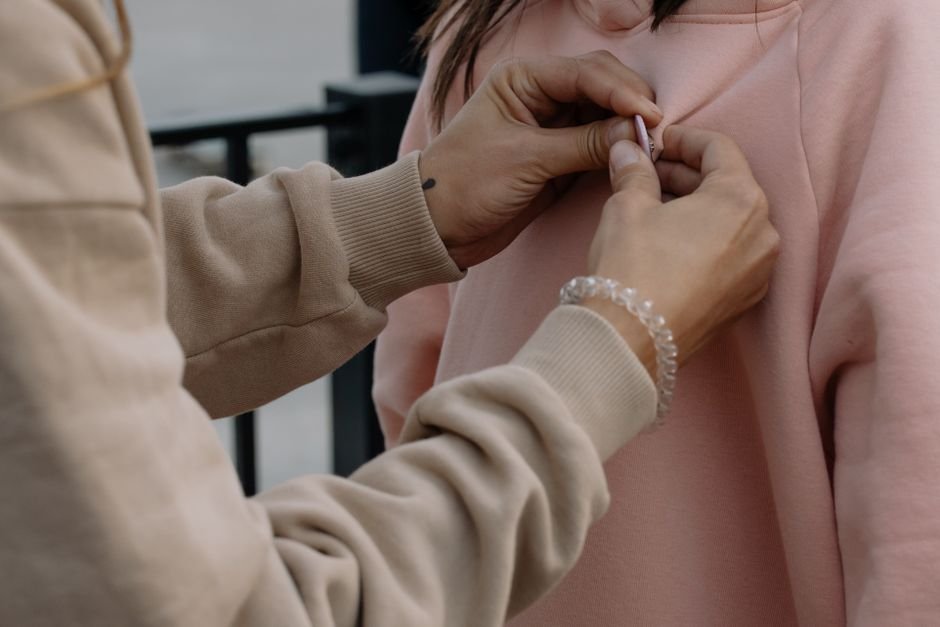 Hands pinning fabric layers together with a straight pin during garment construction