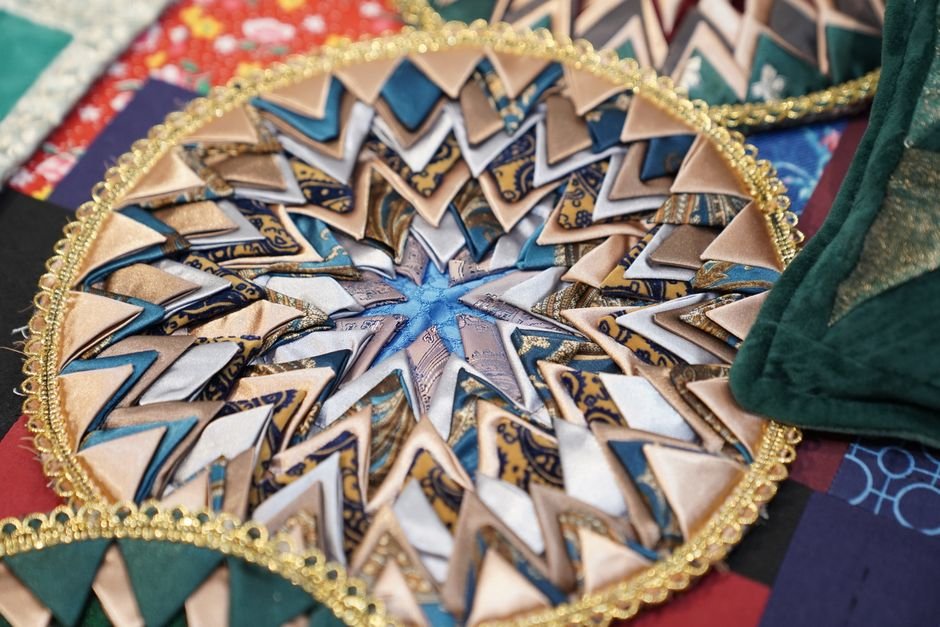 Close-up of an intricately pieced, folded fabric design showing quilted texture and detail