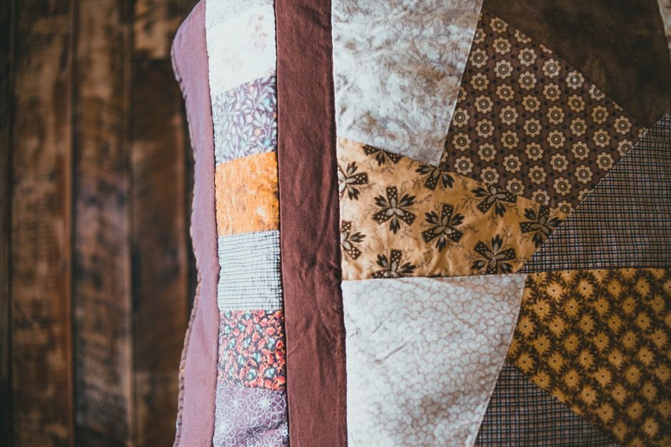 Close-up of an earth-toned patchwork quilt with mixed floral prints