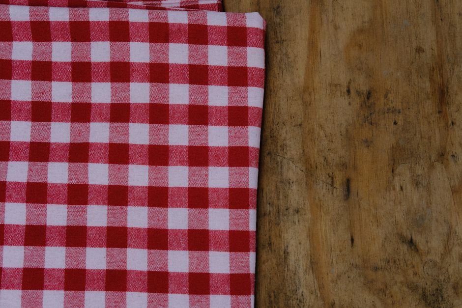Red and white gingham fabric folded on a wooden table showing what is gingham in its classic colorway