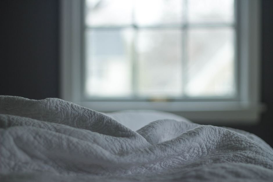 White quilted bedspread folded near a sunlit window