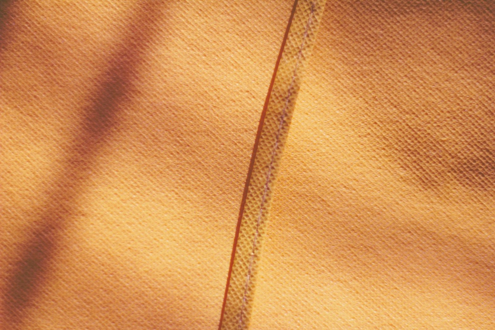 Mustard yellow fabric with a visible stitched seam